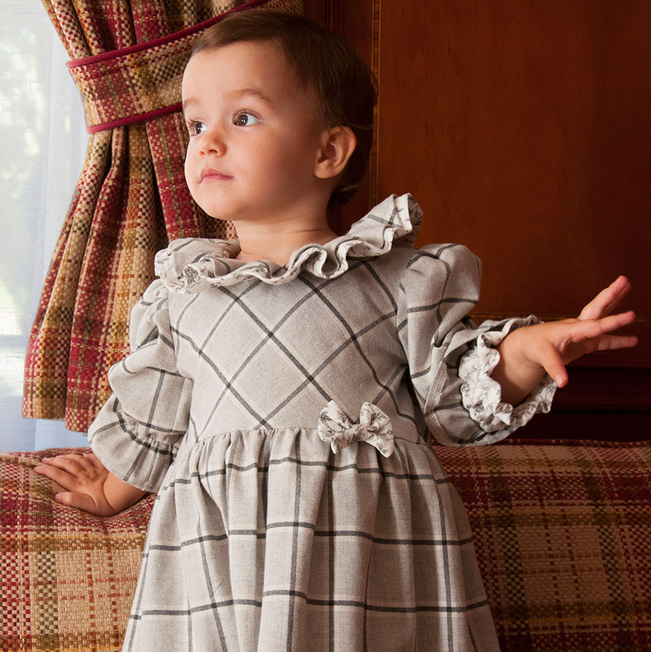 Robe pour bébé en flanelle à carreaux grise avec des volants au col et aux poignets et un petit noeud sur le devant